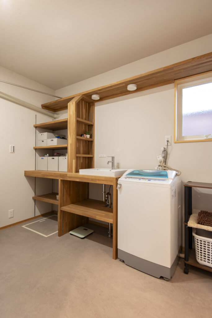 木製の造作洗面台は、コストを抑えつつ無垢の木の温かみが感じられる集成材を採用。家族の衣類やタオルを収納できる棚も一体型で制作し、機能性も兼ねています。