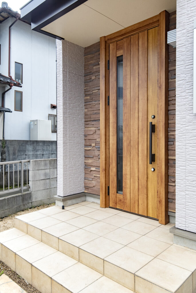 新しく採用した玄関ドアの木目が、シックな外壁に柔らかな温もりをプラスしています。